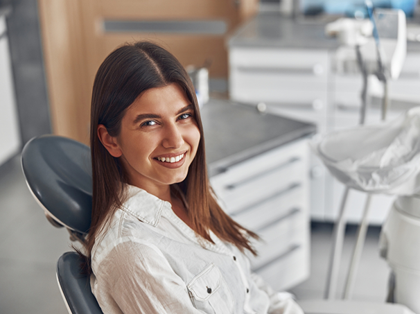 Brunette woman smiling while visiting a dental office in Westbury