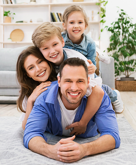 Smiling family of four laying on their living room floor