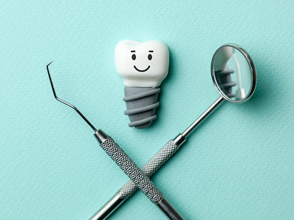 Illustration of a smiling dental implant next to a dental mirror and scaler