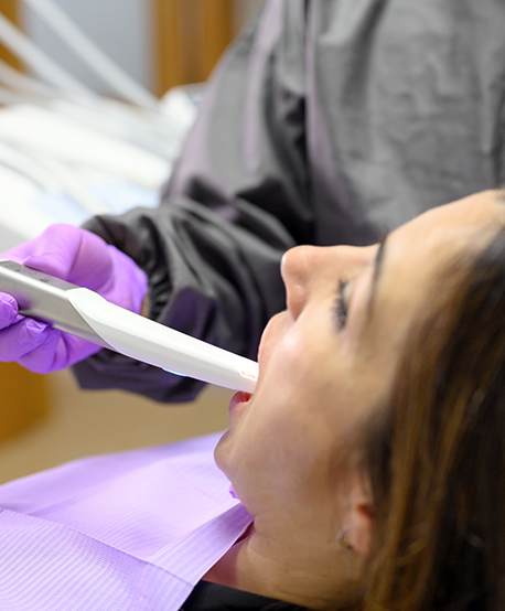 Dental patient having their teeth scanned by a white pen like device