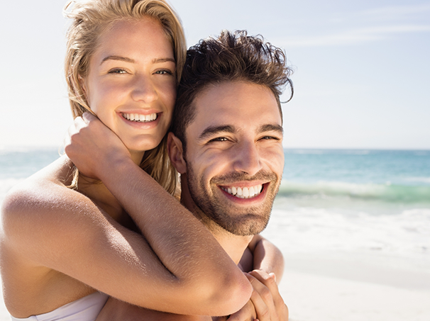 Smiling man and woman embracing on the beach
