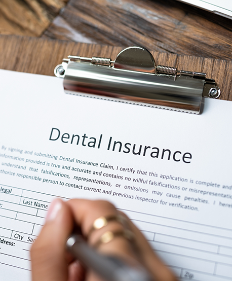 Person filling out dental insurance paperwork on a clipboard