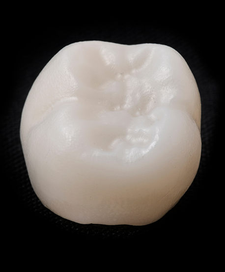 Close up of a tooth colored dental crown against a black background