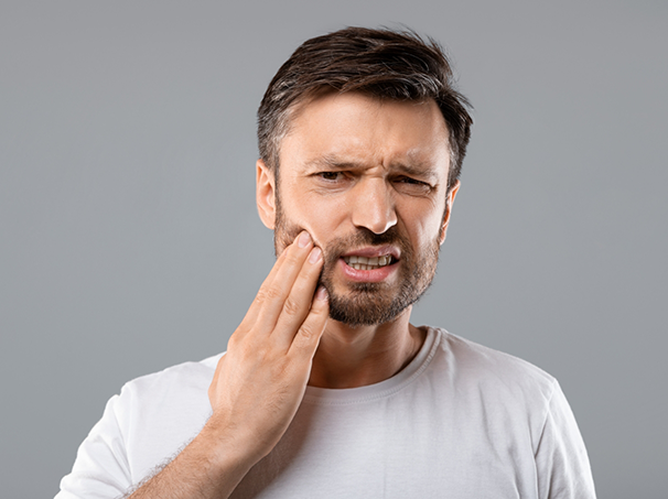 Man holding his cheek in pain before seeing an emergency dentist in Westbury