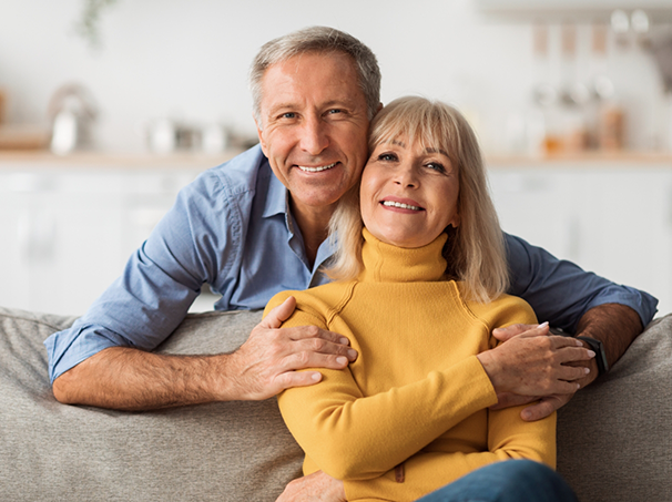 Older couple smiling on their couch at home after preventive dentistry checkup
