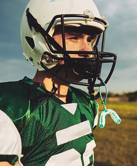 Football player with a mouthguard attached to their helmet