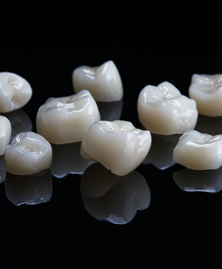 Several tooth colored dental crowns against a black background