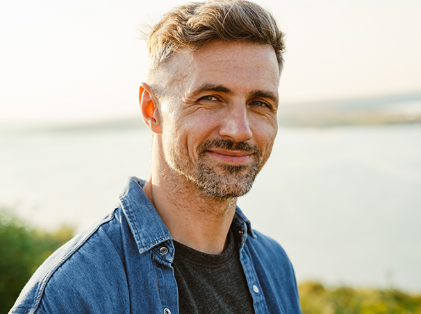 Man in a denim shirt smiling in the sun