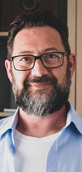 Smiling man in glasses and a pale blue collared shirt