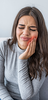 Woman holding the side of her jaw and wincing in pain