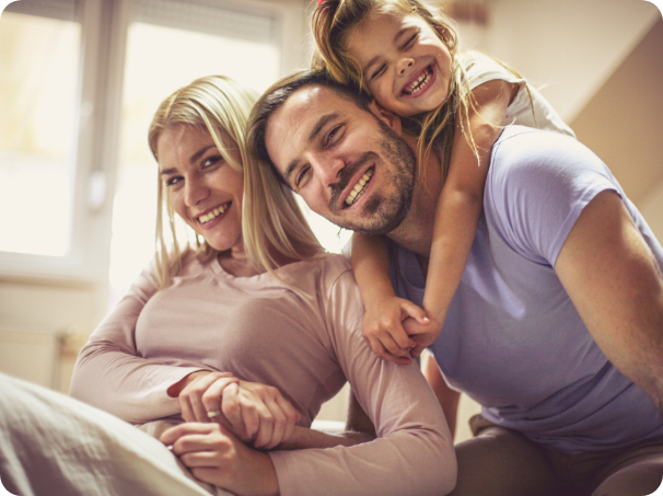 Mother father and young daughter grinning at home