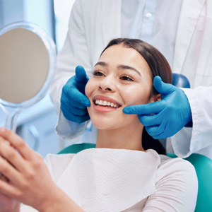Patient smiling at reflection in handheld mirror