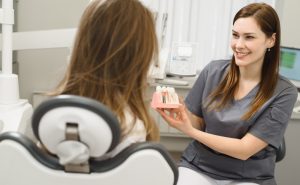 dentist showing patient a dental implant model